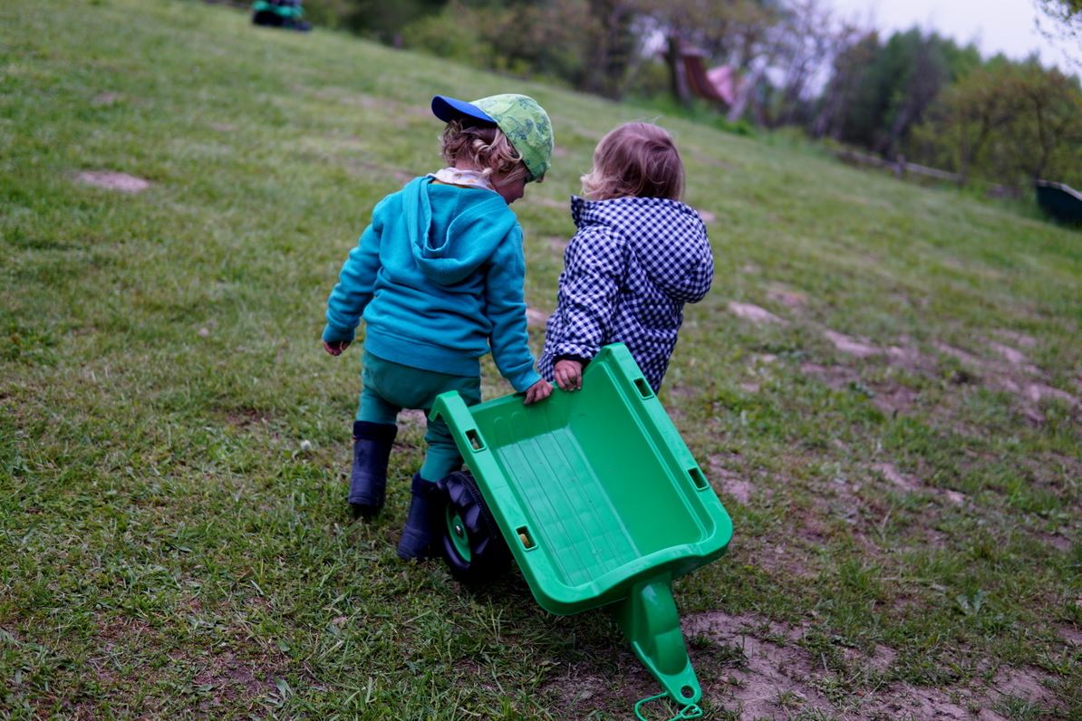 Deux enfants jouant avec la remorque en plastique d'un tracteur
